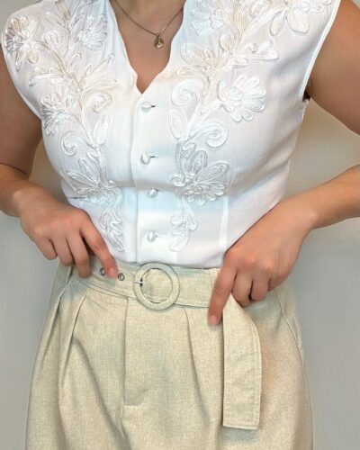 Sleeveless white blouse with wavy decollete